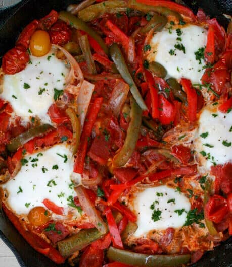 close up image of shakshouka which shows all the tomatoes, peppers, onions, and eggs that go into the dish