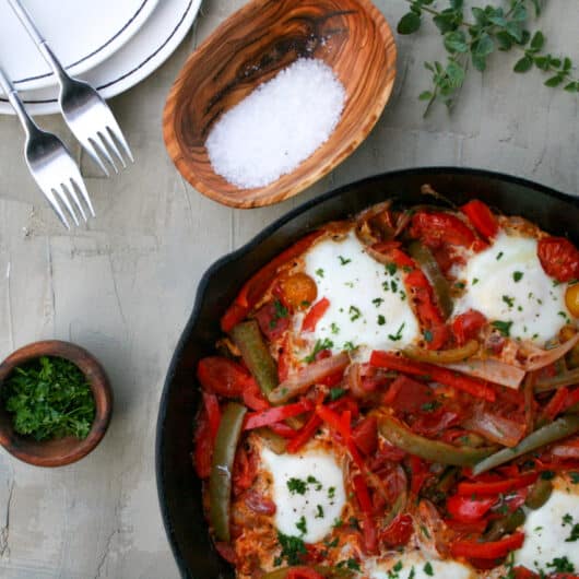 shakshouka in a cast iron skillet with a side of parsley to garnish