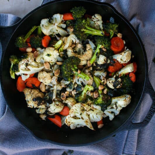 brown butter nori roasted vegetables. This shows carrots, cauliflower and broccoli in a cast iron skillet and drizzled with a brown butter nori sauce