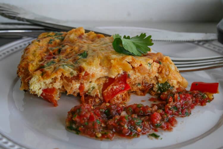 cut slice of huevos rancheros frittata with a side of salsa