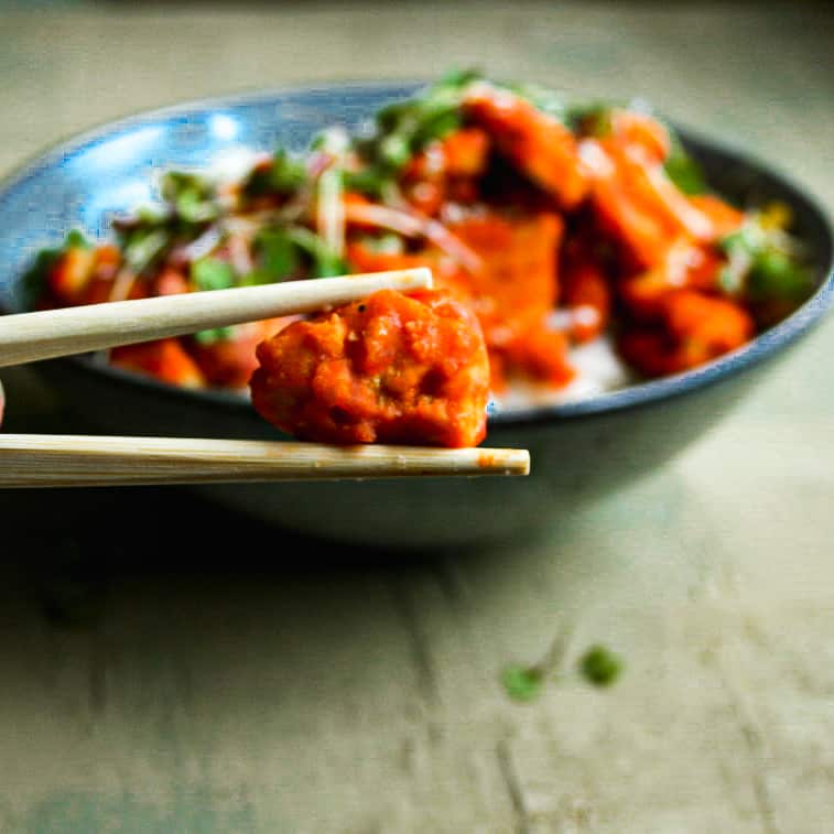 one piece of sweet and spicy tofu in chopsticks