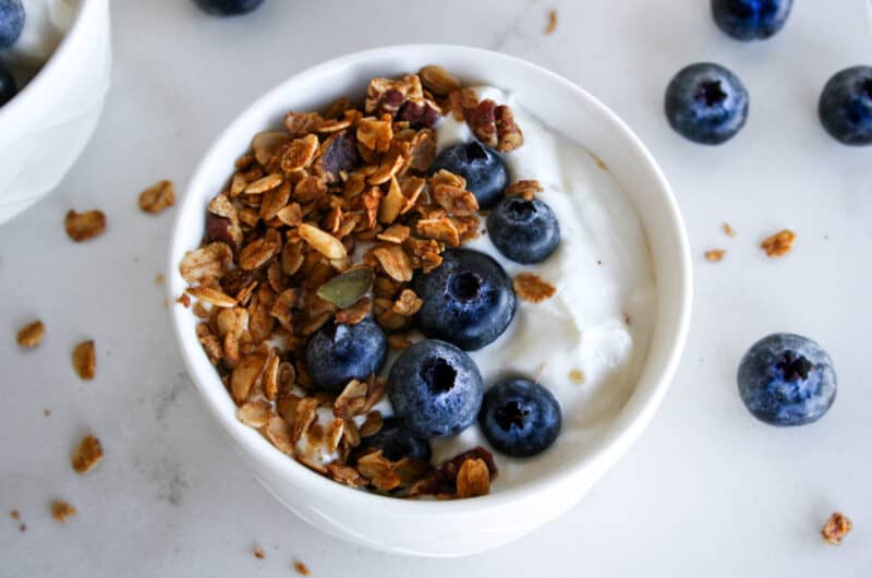 close up of gingerbread granola in a bowl with yogurt and blueberries