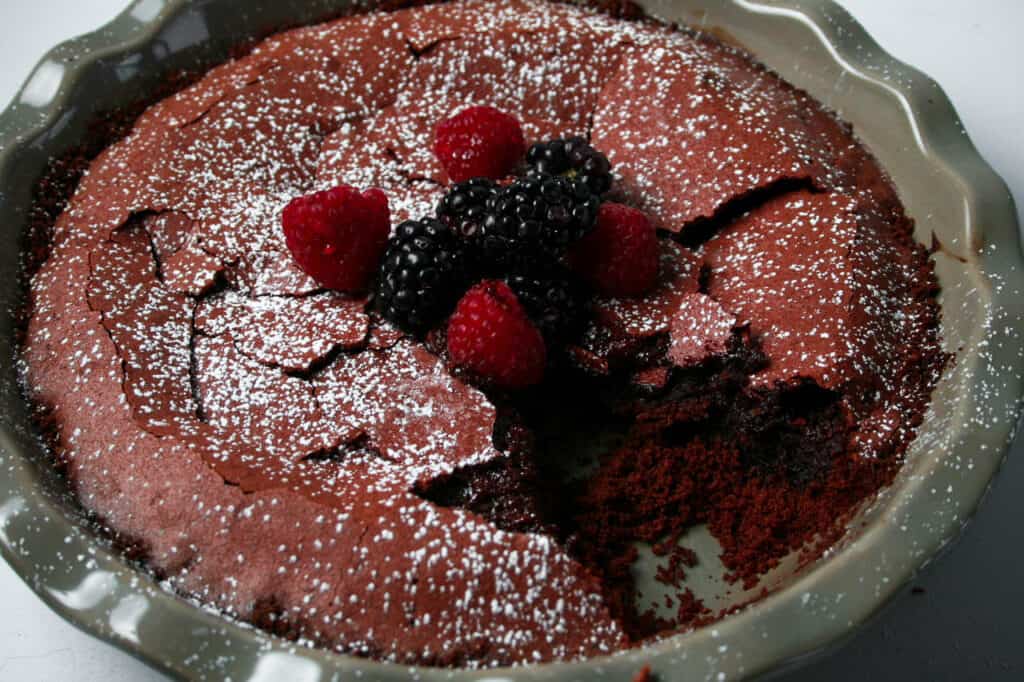 Molten Red Velvet Crack Pie with a slice taken out. Topped with blackberries and raspberries
