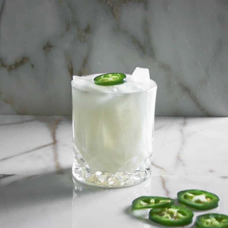 Coconut Mezcal Margarita with a Jalapeño on top. photographed on a marble slab. Los Angeles. Cocktails