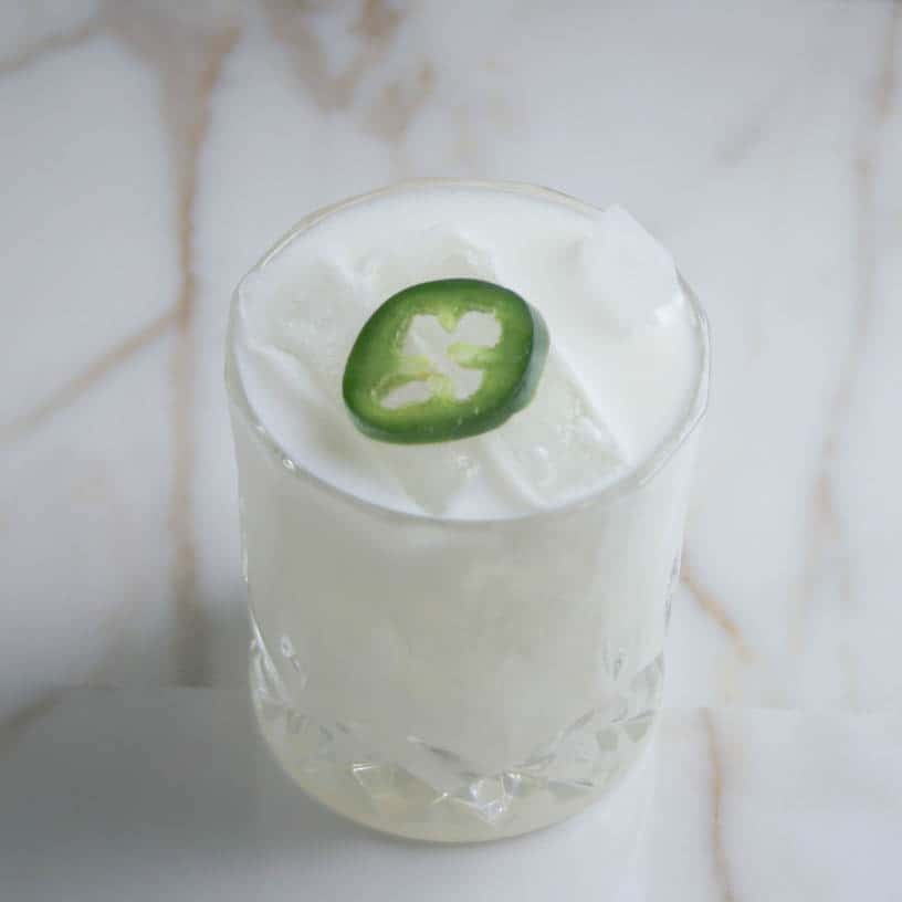 Coconut Mezcal Margarita with a Jalapeño on top. photographed on a marble slab. Los Angeles. Cocktails