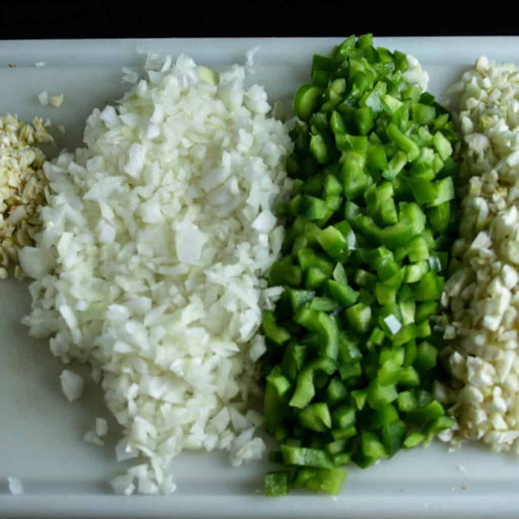 Finely chopped vegetables for seafood cioppino. photographed on a white cutting board