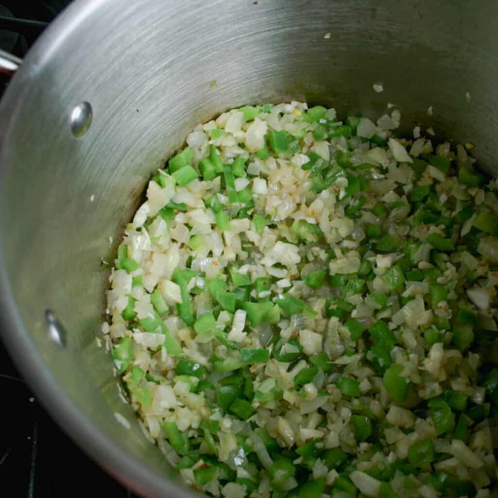 Process shot of seafood cioppino. Vegetables sautéing in a large pot