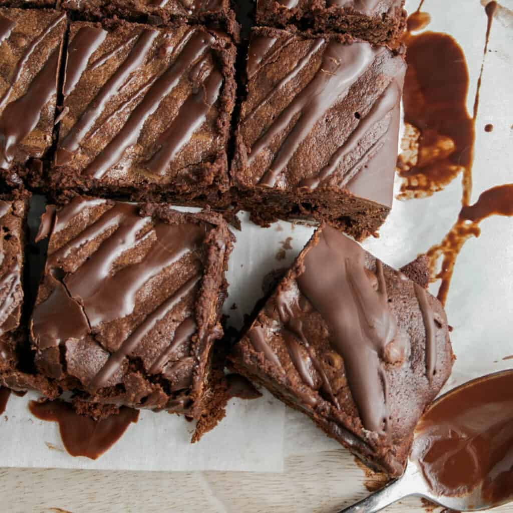 Double Chocolate Irish coffee Brownies with a chocolate drizzle. Photographed on a sheet of parchment paper on a Calcutta marble board
