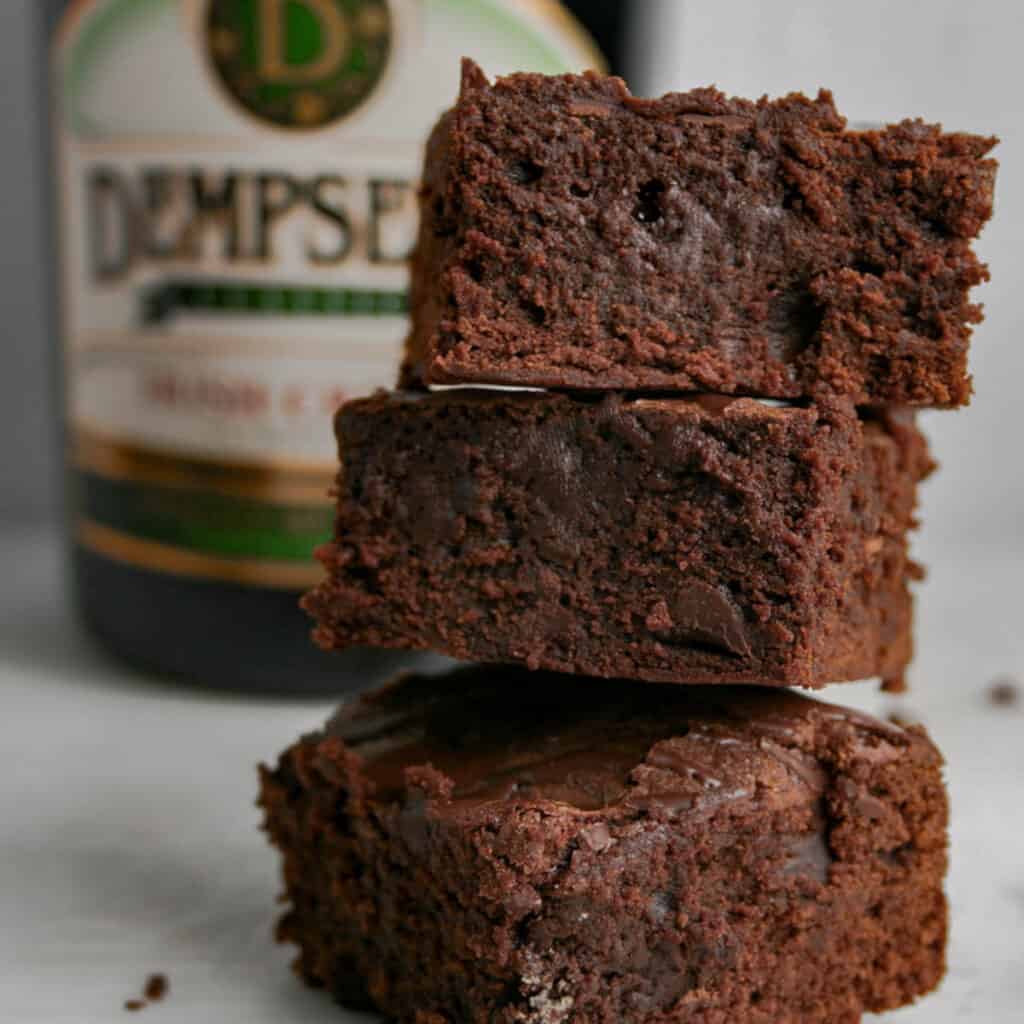 Stack of Double Chocolate Irish coffee Brownies. with a bottle of Dempsey's Irish cream in the background