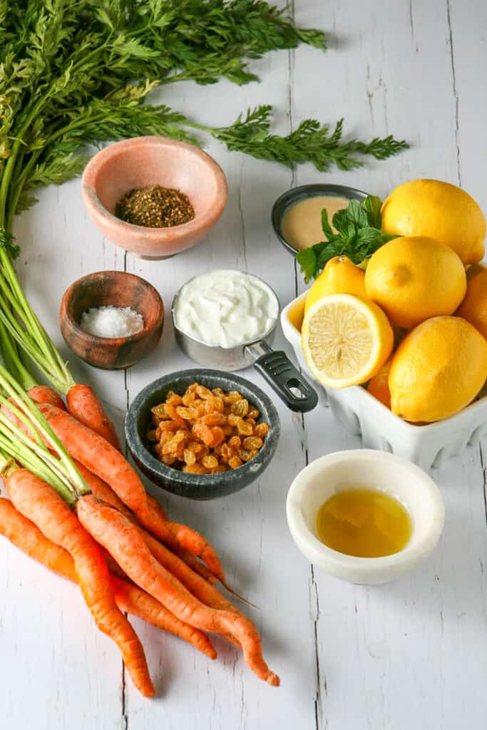 Ingredient process shot for Grilled Mediterranean Carrots. Photographed on a white wood table. 