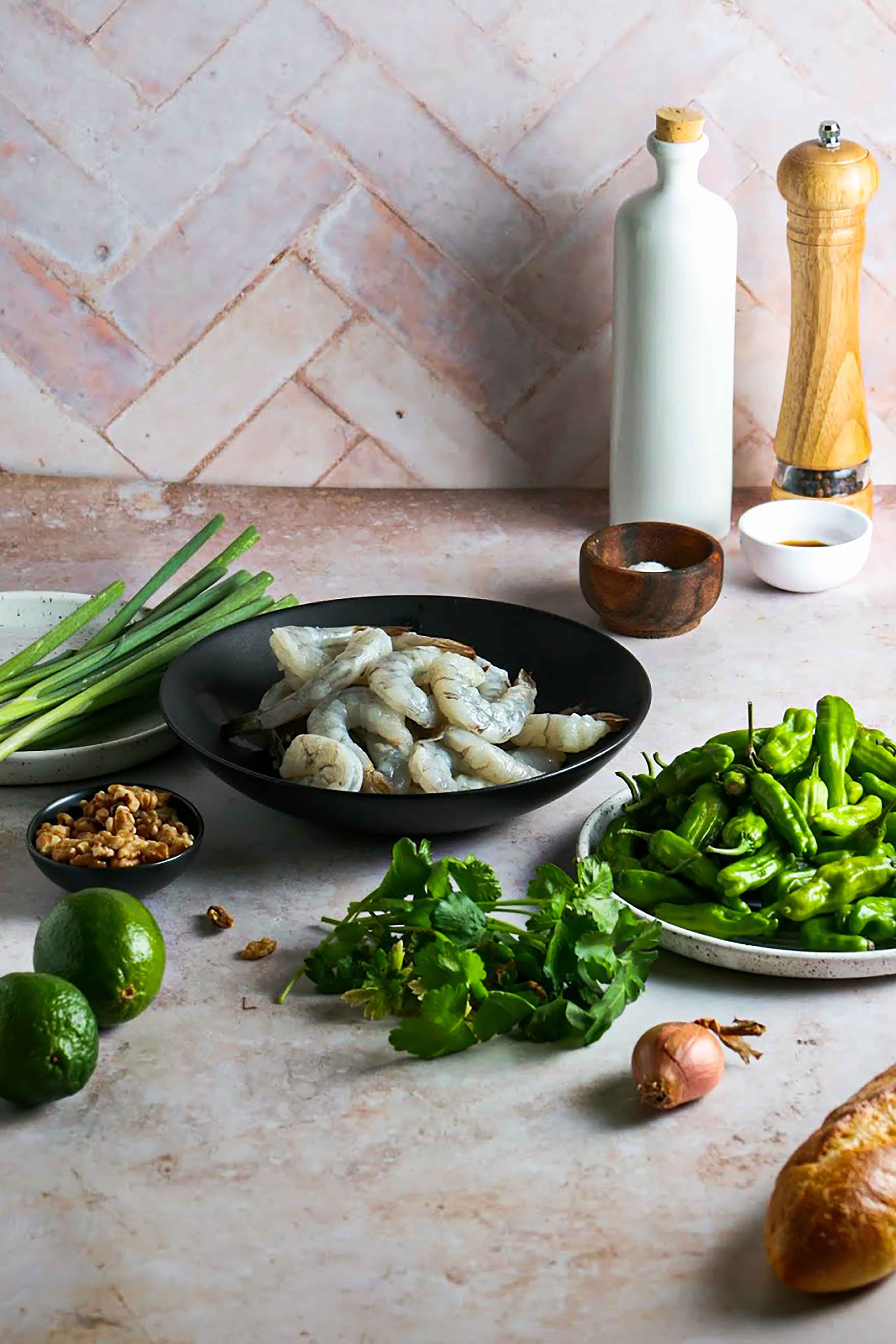 Ingredient photograph for Grilled Shrimp with Shishito Pepper Gremolata. Photographed on beige marble with herringbone tile background. 