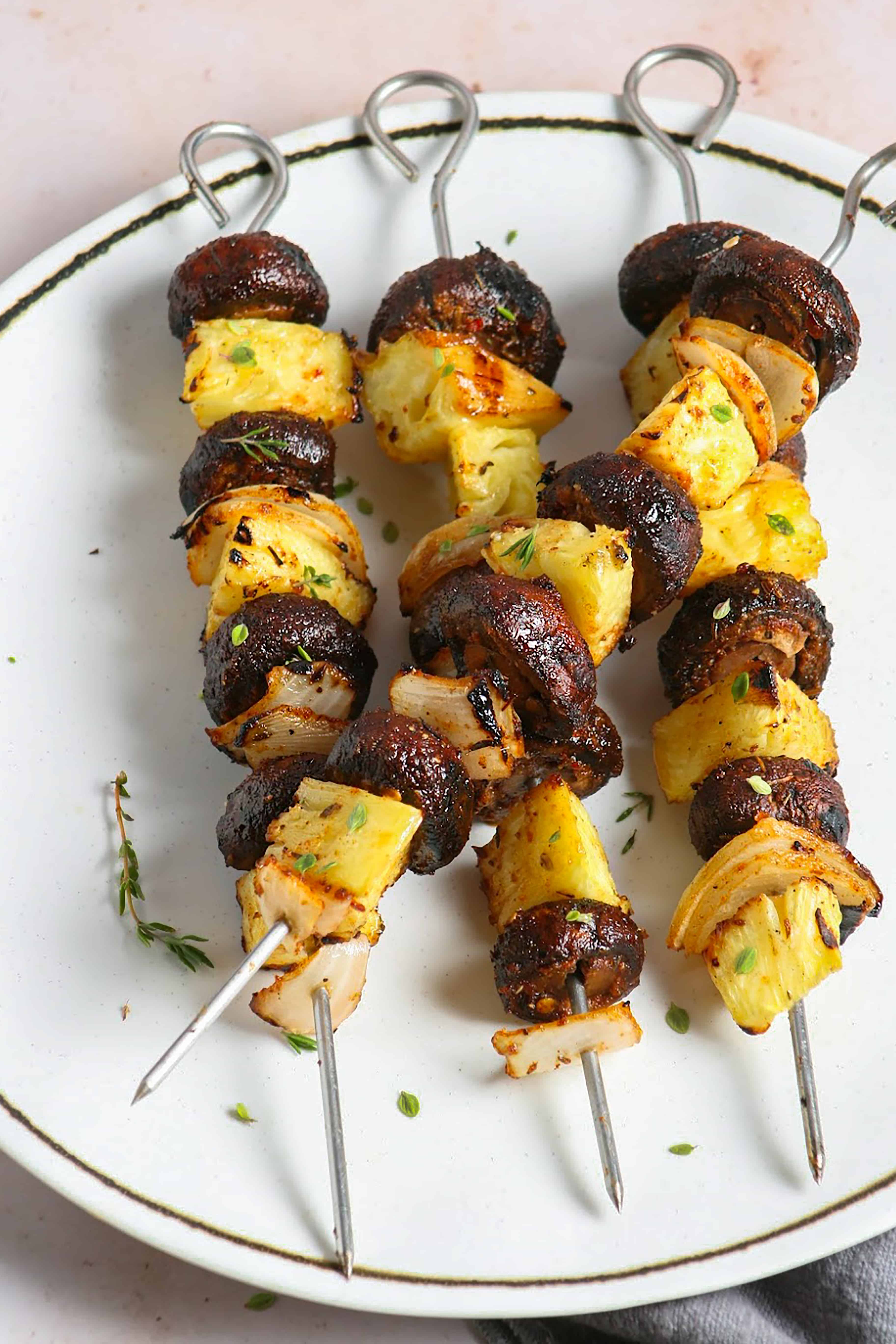Vegan Jamaican Jerk Mushroom Skewers. made on the grill. Photographed on a white plate on a stone table