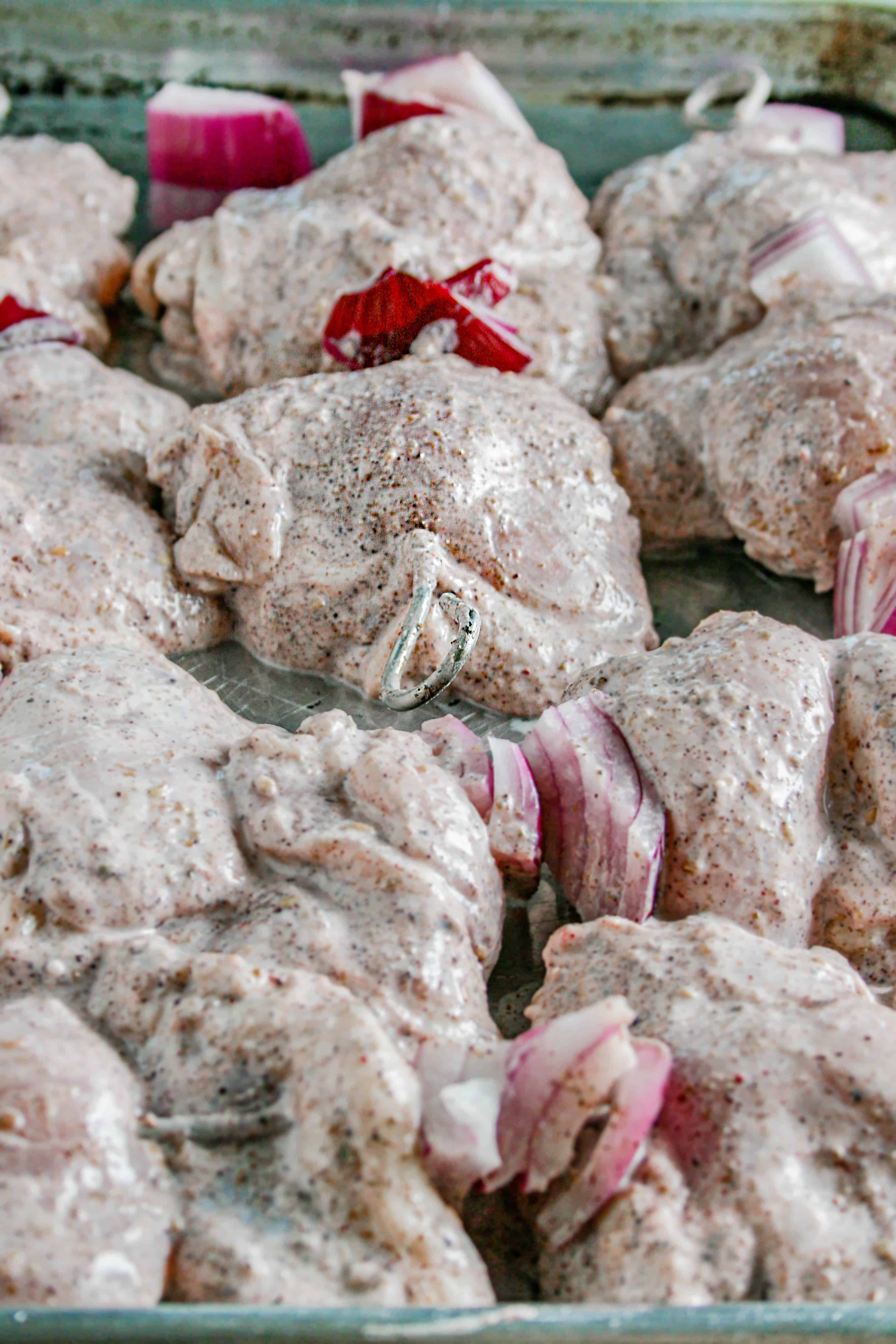 Process shot of Process shot of za'atar grilled chicken thighs. threaded on the skewer ready to be grilled