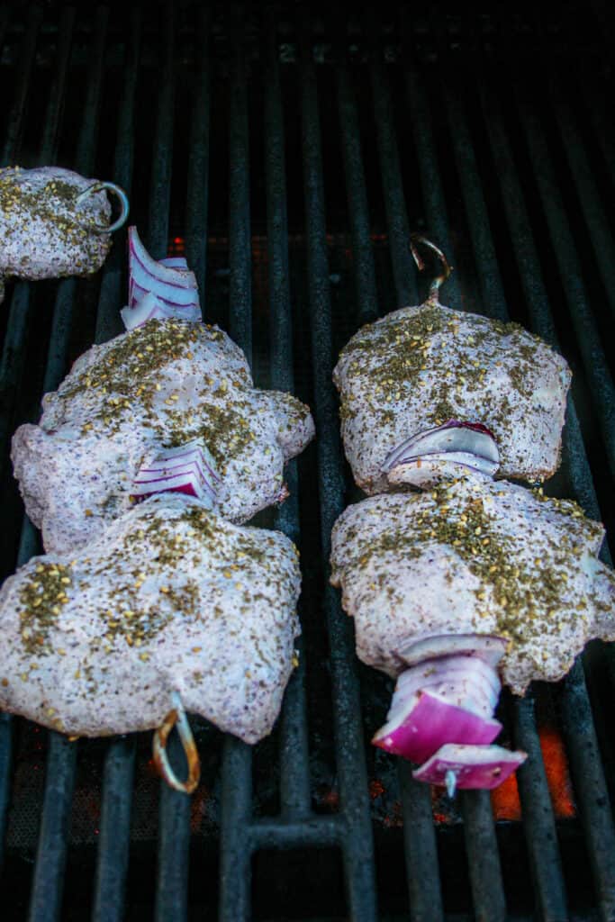 Process shot of grilling for  za'atar grilled chicken thighs. threaded on the skewer ready to be grilled