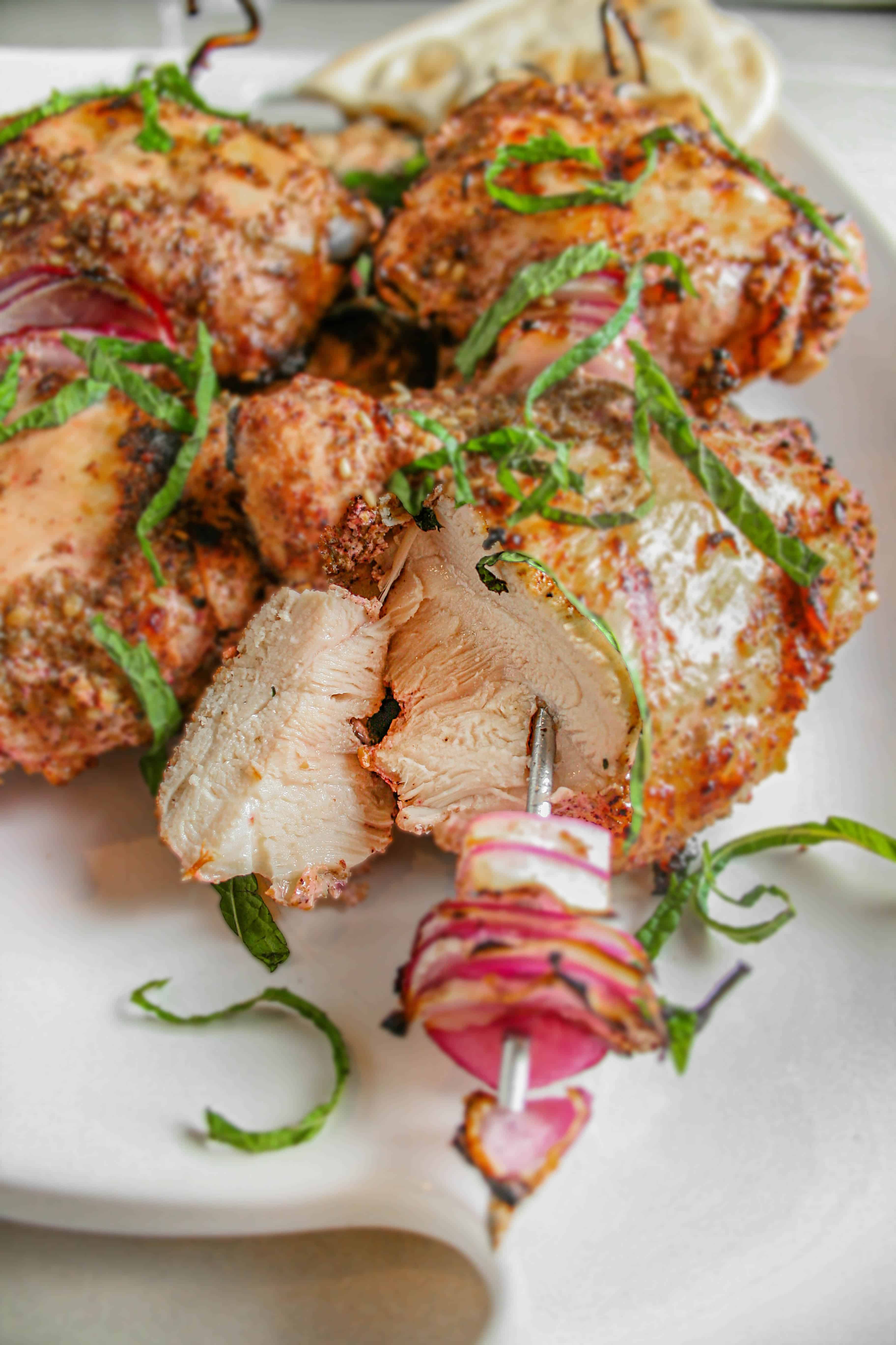 Za'atar Grilled Chicken Thighs on a white serving platter garnished with fresh mint