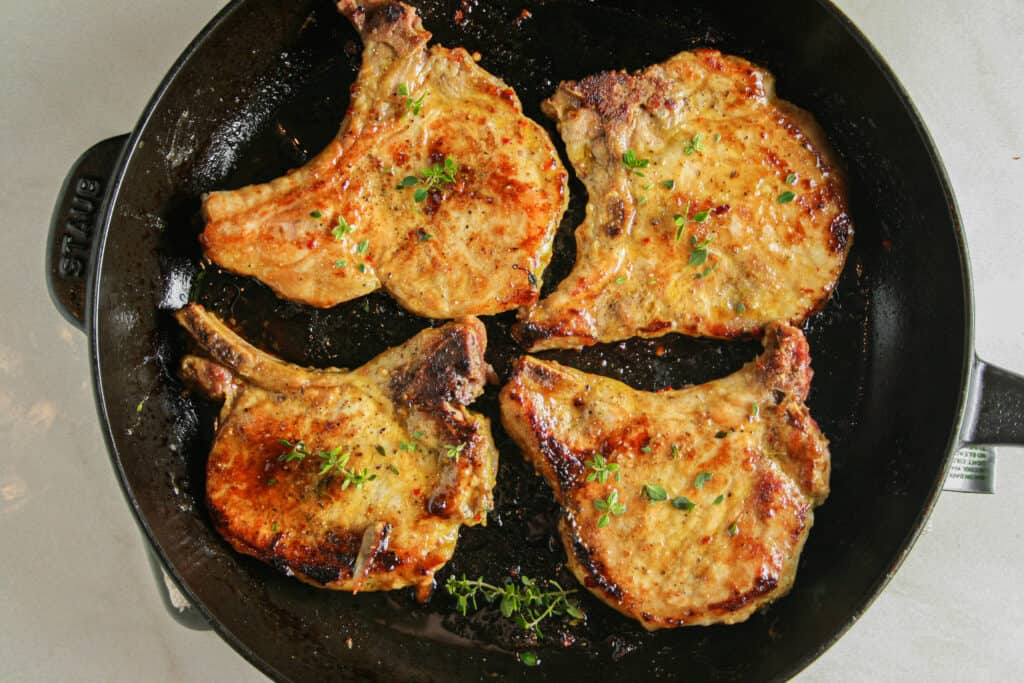 Pan Seared Maple Pork Chop photographed in a black Staub cast iron skillet