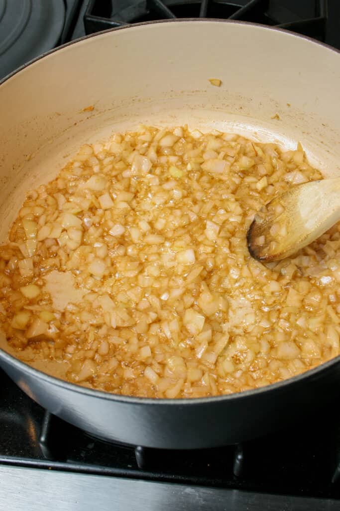 Photograph of onion and garlic cooking in browned butter in a dutch oven