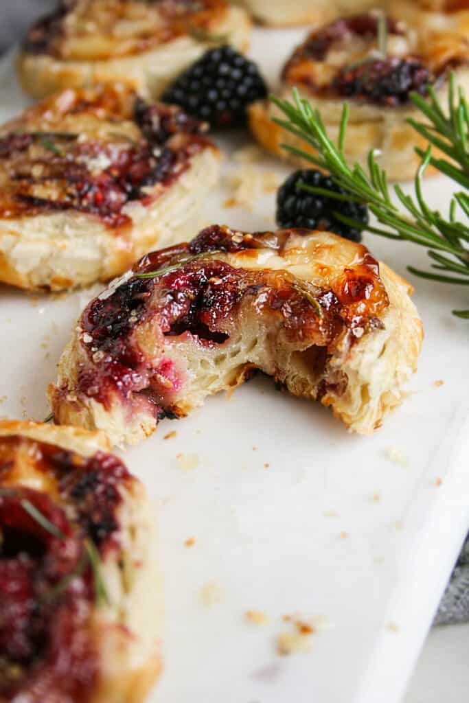 Photo of Photo of Blackberry Brie Pinwheel with a bite taken out on a marble serving board