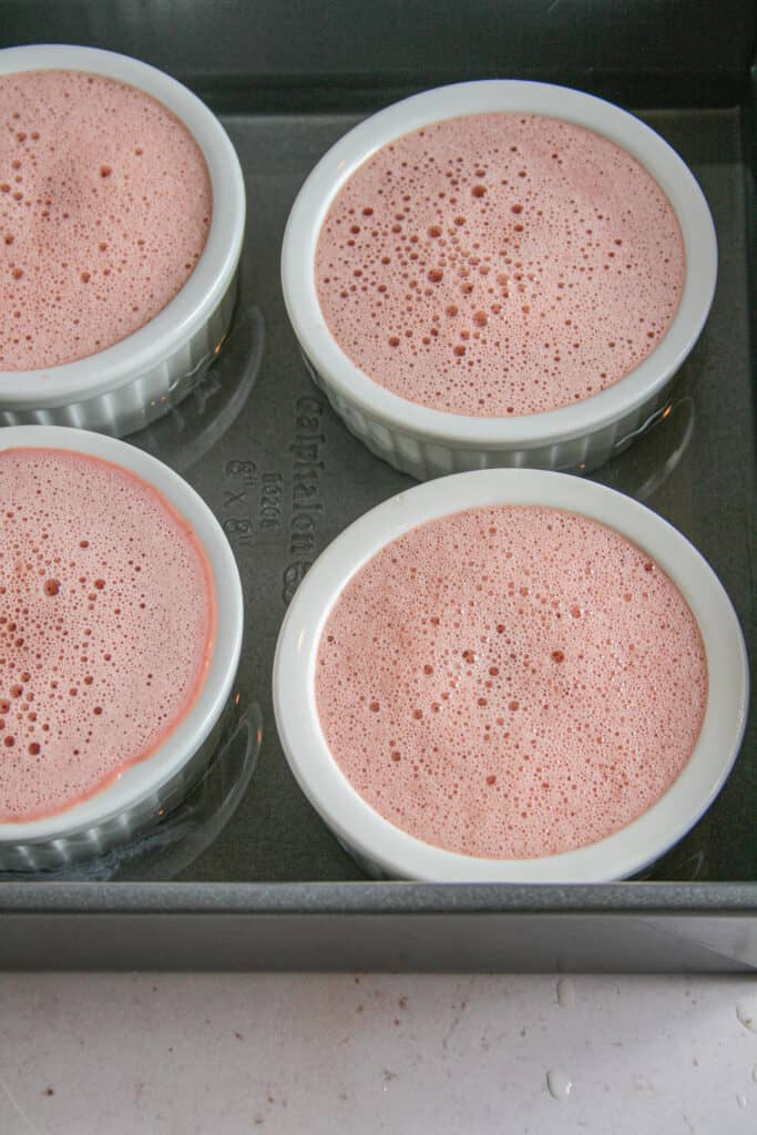 Ramekins filled with red velvet creme brulee custard before baking