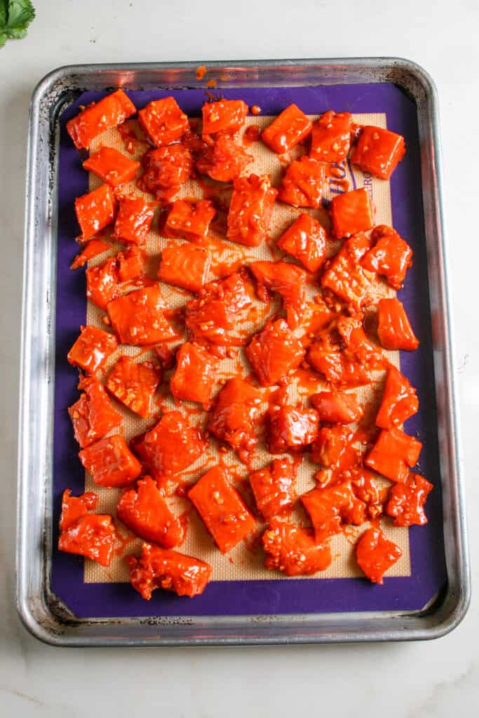Spicy salmon lined on baking sheet. uncooked