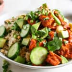 Spicy salmon rice bowl with toppings of cucumber, cilantro, cashews, green onions