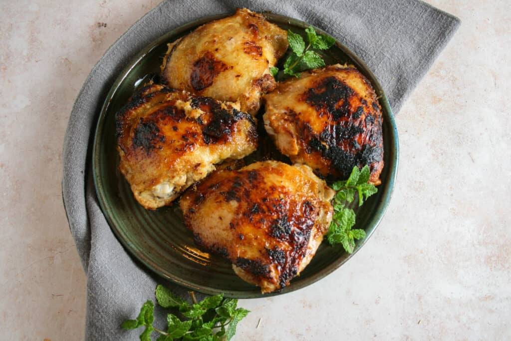 Vietnamese Lemongrass Chicken Thighs served on a green plate. Pictured with a grey napkin and mint leaves