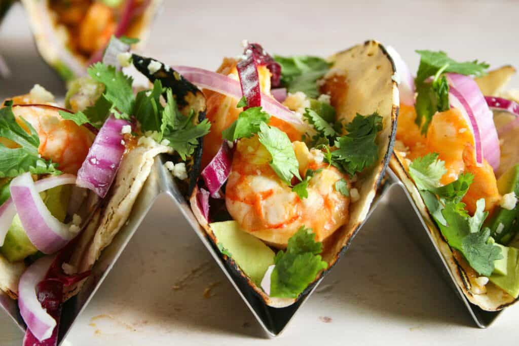 Chili mango shrimp tacos in steel taco holders