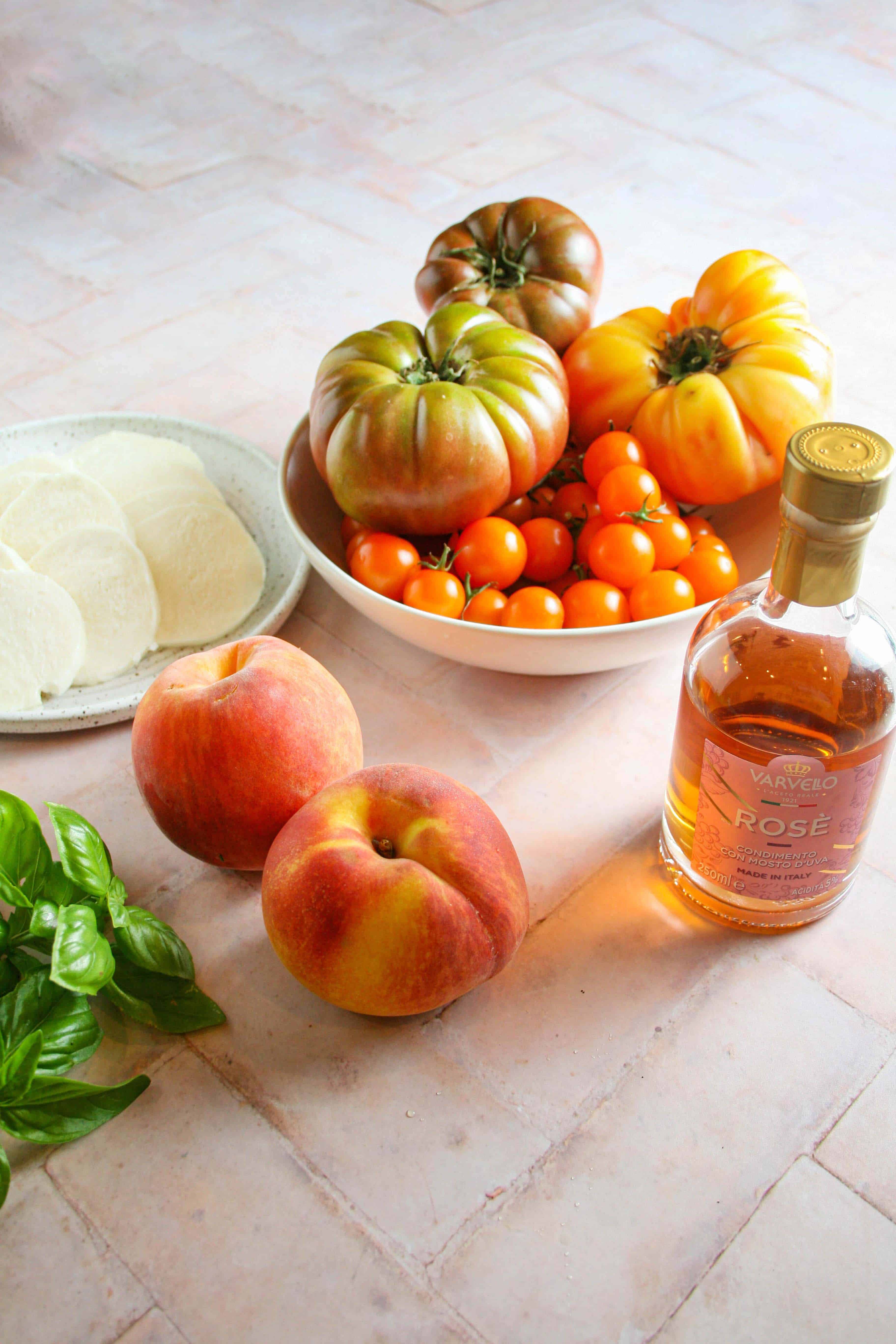 ingredient photograph showing tomatoes, peaches, vinegar, basil, and cheese