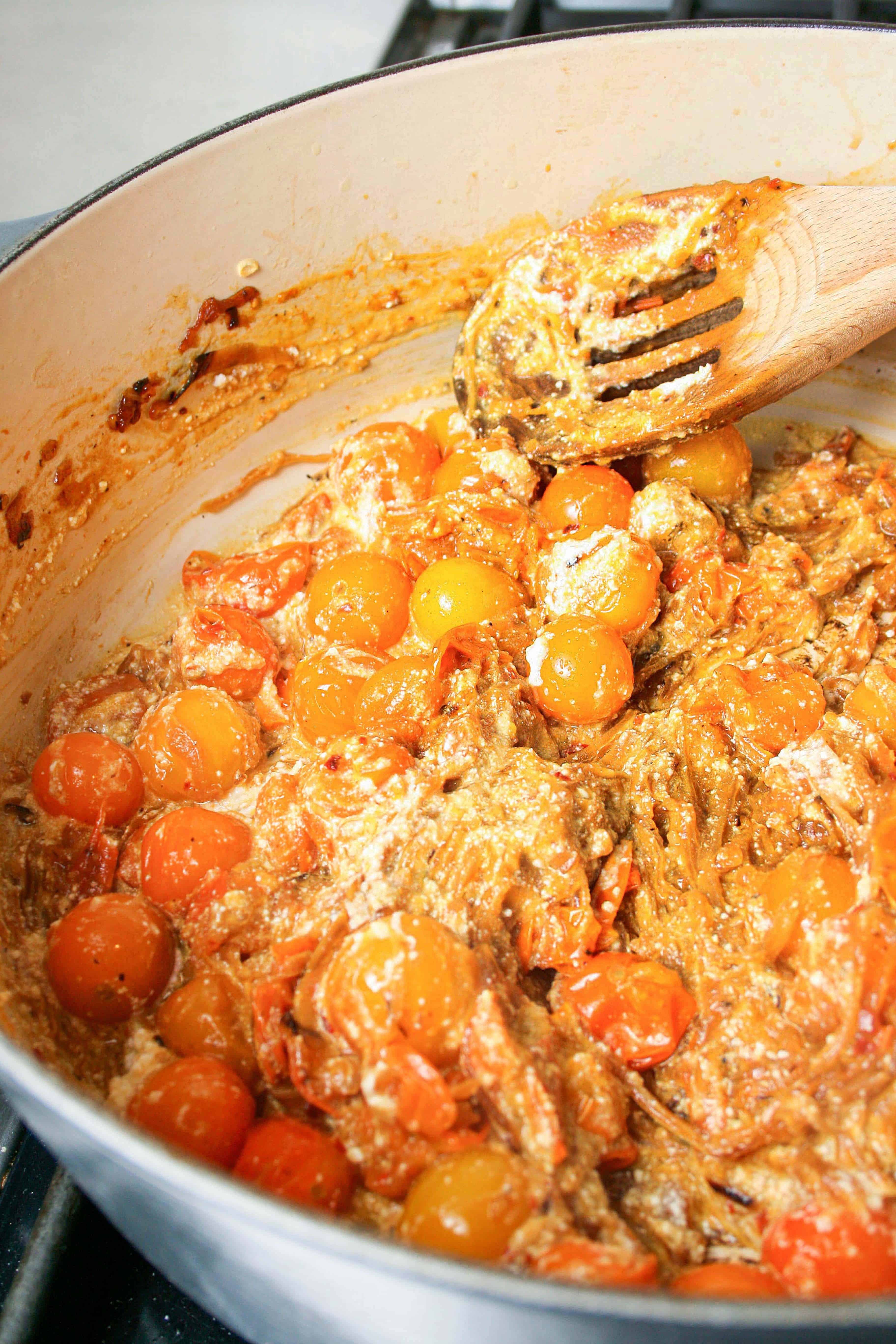 Photograph of the sauce for caramelized onions and sun gold tomato sauce being cooked in a dutch oven pan