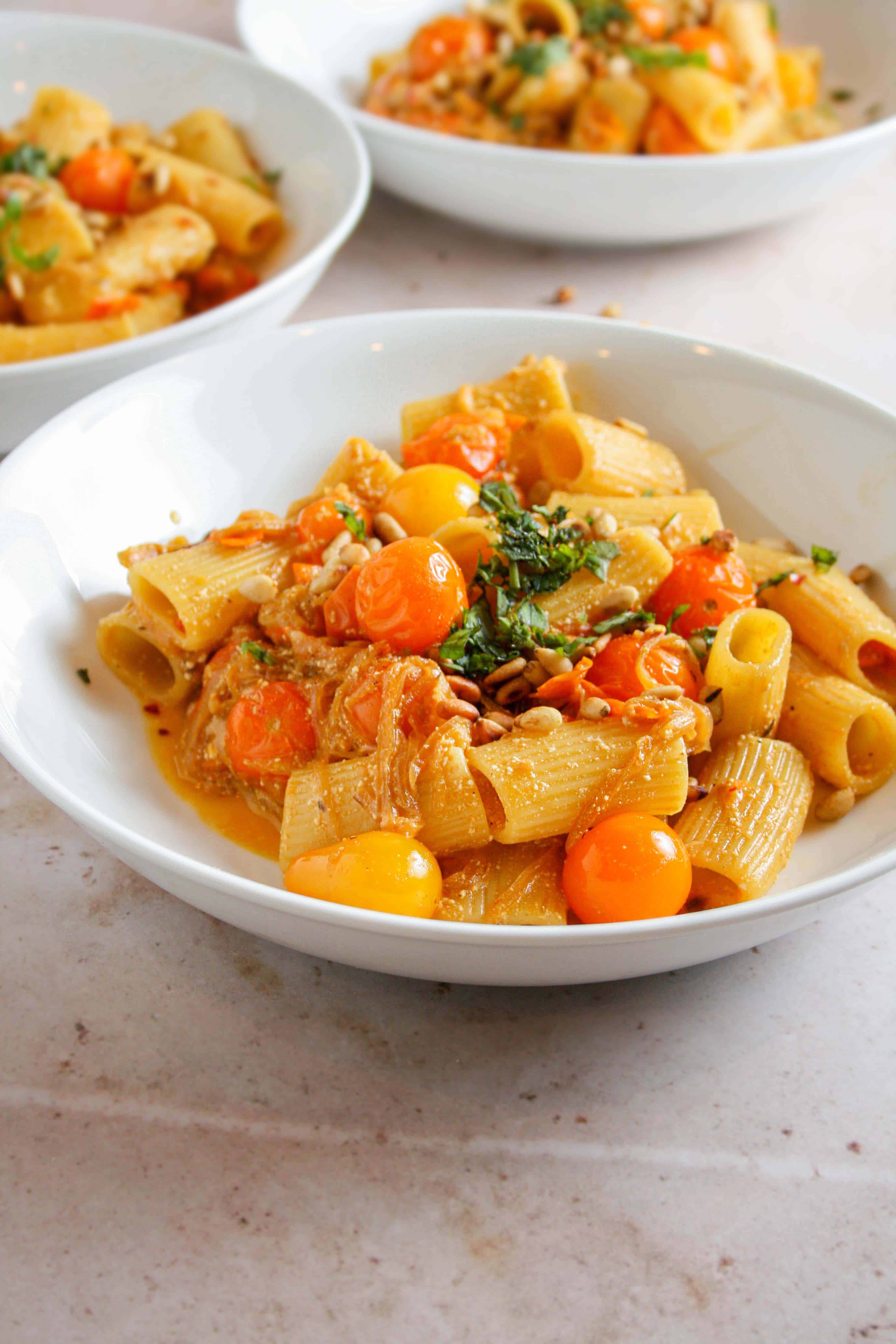 Hero photograph of caramelized onion and sun gold tomato pasta