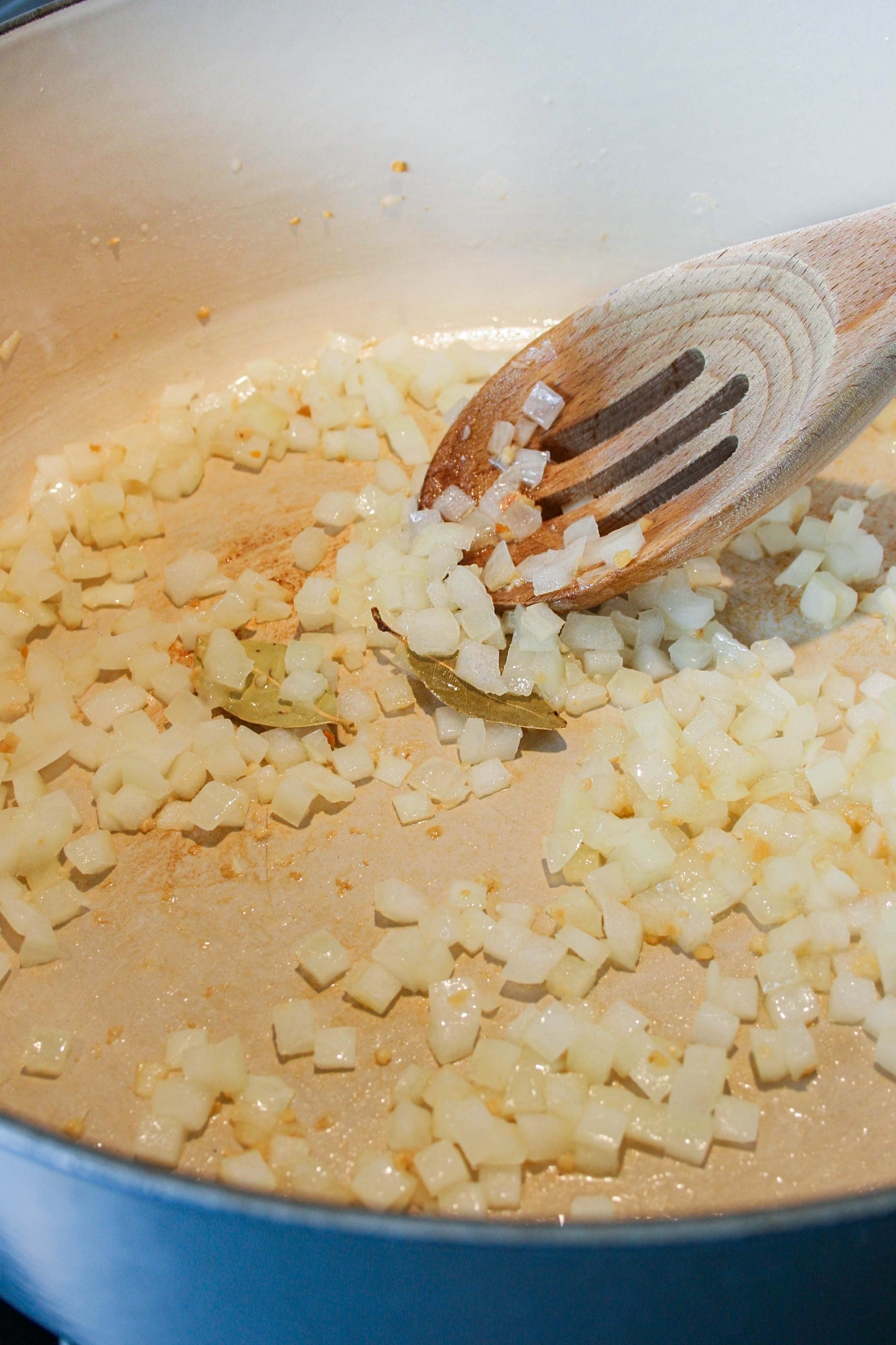 Diced onions cooking in a blue dutch oven