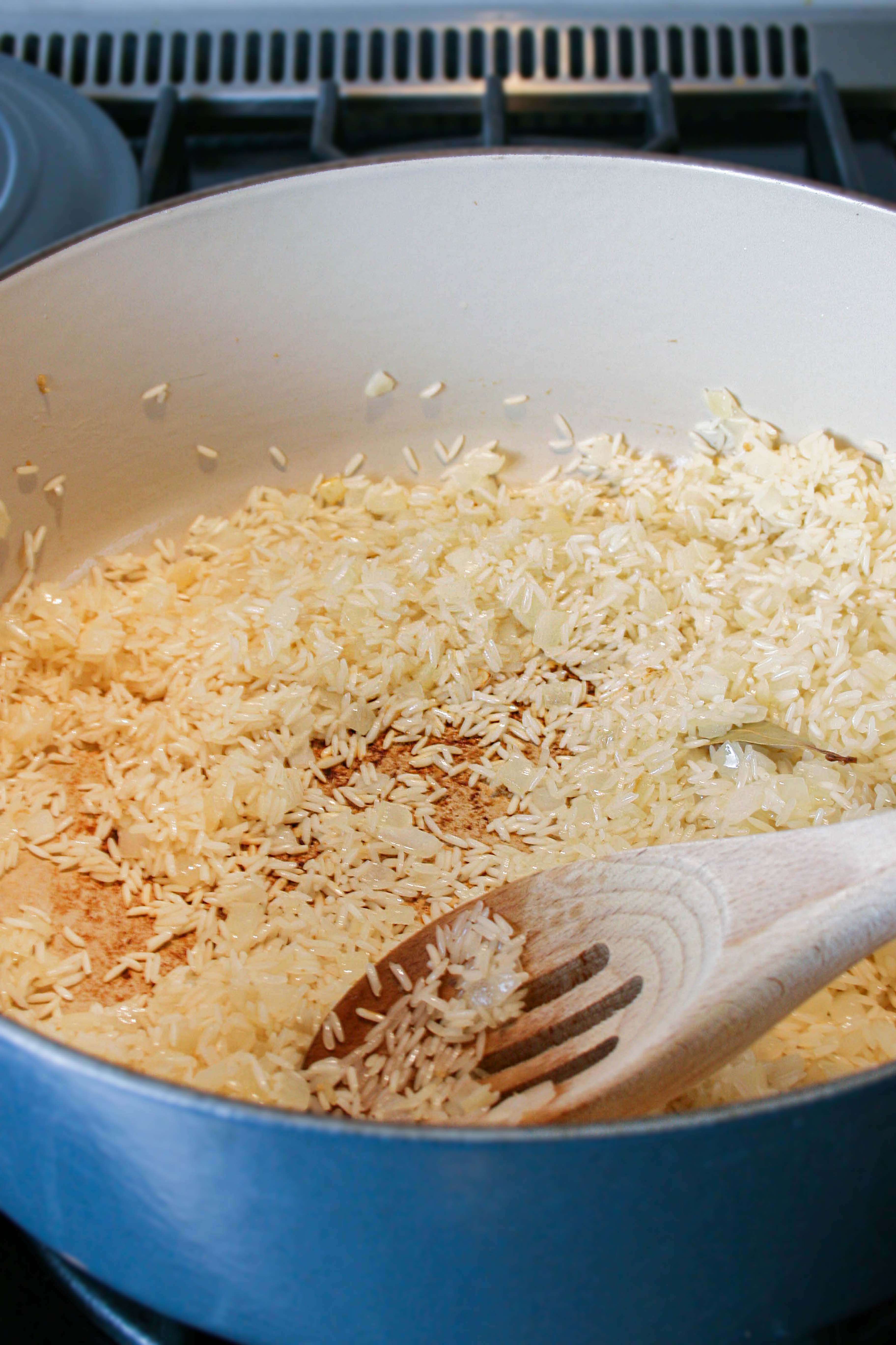 Rice toasting with aromatics in a blue dutch oven